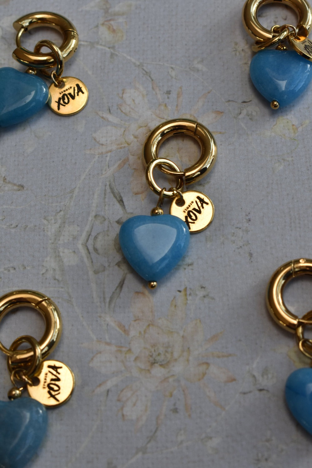 Goudkleurige kleine hoops oorbellen met blauwe hematiet kraal in een hartje en goudkleurige bedel | Studio XOVA X.262