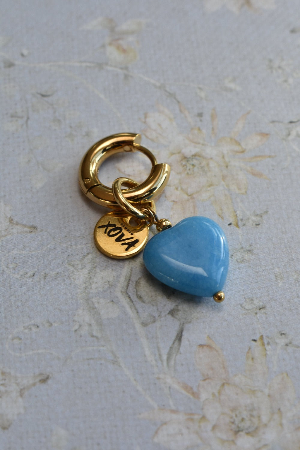 Goudkleurige kleine hoops oorbellen met blauwe hematiet kraal in een hartje en goudkleurige bedel | Studio XOVA X.262